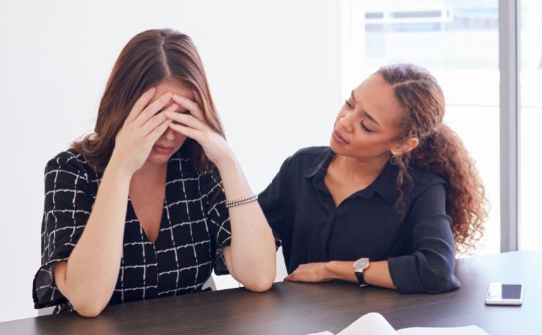 shutterstock_2460313677-1775133896 Business woman, management and stress in burnout, friends and advice with empathy in office. Anxiety, pressure and headache for employee for paperwork, review and task by frustrated or team support