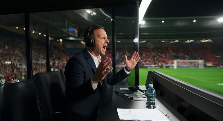 Indoor photo of football match male commentator from commentary box expressing for goal