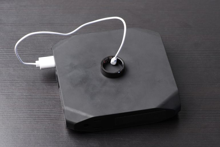 shutterstock_2553462413-1781004679 Smart ring is connected to a charging cable from power bank.