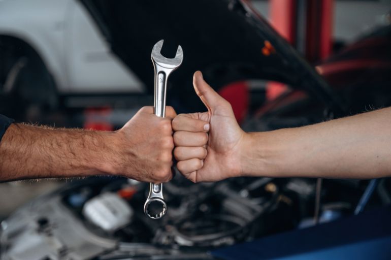 shutterstock_2605456115-1769942434 Hands of mechanic and client, holding tool, car service station.
