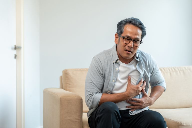 shutterstock_2625572751-1769182695 Old man senior he felt a pain in his chest held his hand and squeezed it. Mature Heart attack that needed treatment. Sitting on sofa couch in living room at house; Shutterstock ID 2625572751; purchase_order: aj; job: ; client: ; other: