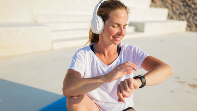 shutterstock_2705337701-1780303942 Woman checking smartwatch while exercising outdoors