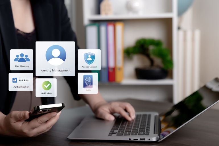 Person using smartphone and laptop with virtual identity management interface, illustrating authentication, access control, verification, MFA, and user directory for secure digital identity, enterprise security, and modern account protection.