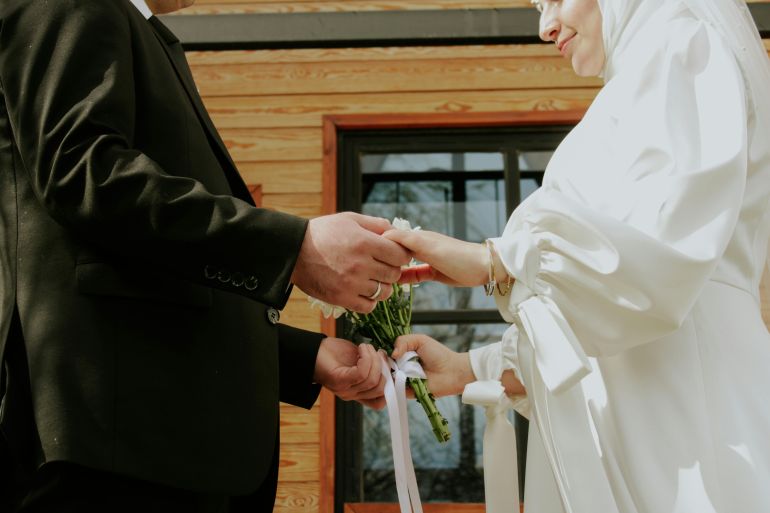 A bride and groom exchange vows and rings during an outdoor wedding ceremony.
