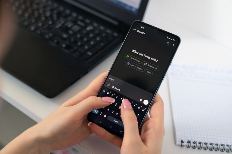 2d8b4d8b3d98ad8b4d98a-1763025018 Kyiv, Ukraine - July 20, 2025: Woman typing on smartphone with ChatGPT app open, sitting at desk with laptop and notepad, using AI chatbot technology.; Shutterstock ID 2655690843; purchase_order: سيس; job: ; client: ; other: