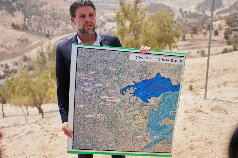 5641-1771537927 CORRECTS DAY Israeli Finance Minister Bezalel Smotrich holds a map that shows the E1 settlement project during a press conference near the settlement of Maale Adumim, in the Israeli-occupied West Bank, Thursday, Aug. 14, 2025. (AP Photo/Ohad Zwigenberg)
