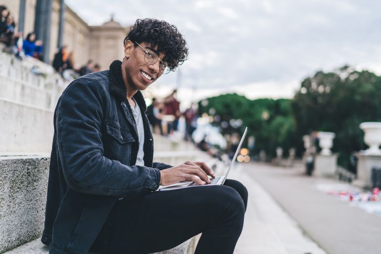 Portrait of happy digital nomad in optical spectacles for provide eyes protection resting near Spanish architecture and smiling at camera while working ... See More by BullRun @ادوبي ستوك