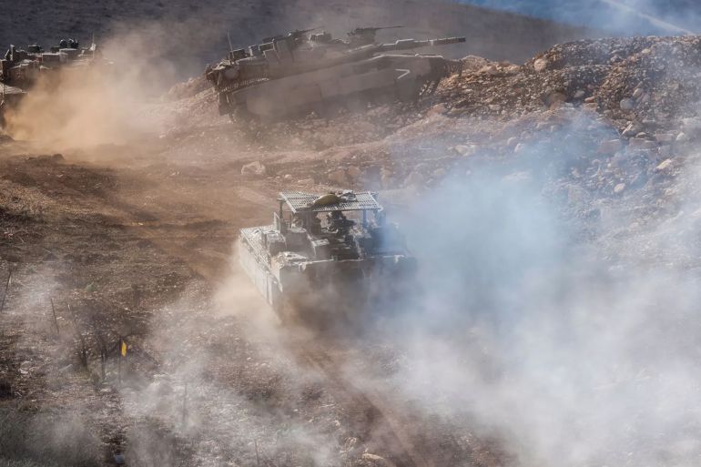 Israeli military tanks patrol close to a concrete wall along the border fence separating northern Israel from southern Lebanon on November 24, 2025. Hezbollah held the funeral on November 24 for its top military chief and other members of the militant group a day after Israel killed them in a strike on Beirut's southern suburbs.