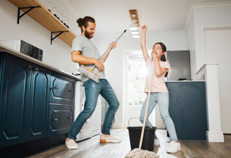 Having fun doing chores, dancing and singing father and daughter cleaning the living room together at home. Carefree, happy and cheerful parent bonding, doing housework and playing with little girl. adobe stock