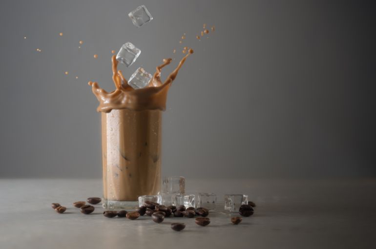 adobestock_220693537-1782939350 Iced coffee splash with ice cubes and beans against grey concrete المصدر: أدوبي ستوك