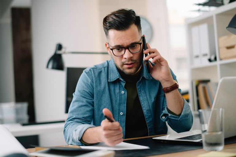 adobestock_327521850-1784563719 Businessman in office. Handsome man talking on phone at work. المصدر: أدوبي ستوك