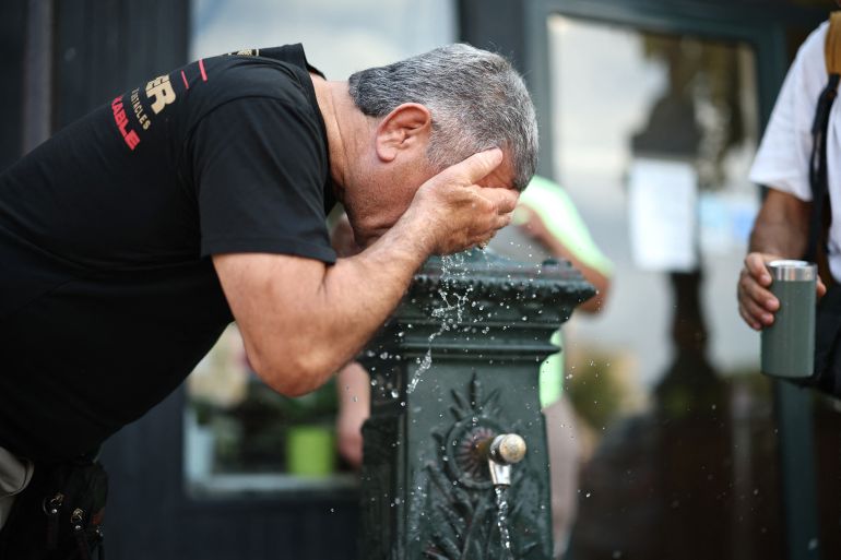 afp_6a3426c6b3fb-1781802694 A man cools off at a public drinking fountain in Paris on June 18, 2026. (Photo by SIMON WOHLFAHRT / AFP)