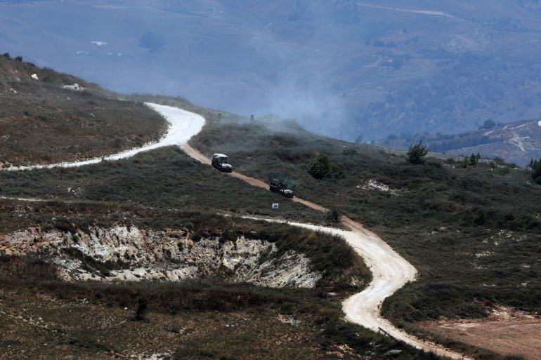 afp_6a479c1dc828-1783077917 This picture taken from a position in the Upper Galilee in northern Israel shows Israeli military vehicles driving past houses destroyed in Israeli strikes in the southern Lebanese village near the Israel-Lebanon border, on July 1, 2026.