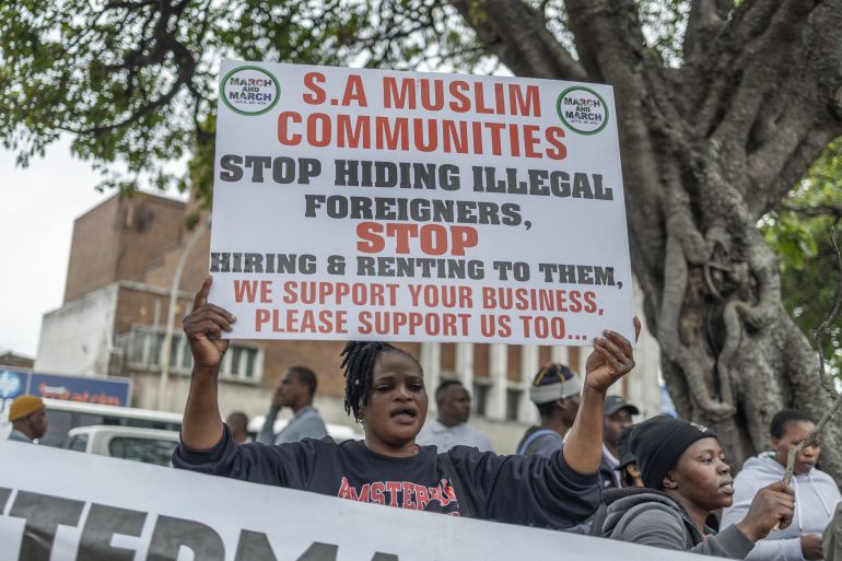 A protester holds a placard during a demonstration by the "March and March" movement marking an unofficial deadline set by citizen-led groups for undocumented foreign nationals to leave South Africa, in Durban, on June 30, 2026.