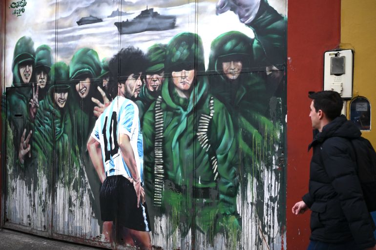 afp_6a59303c942d-1784229948 A man walks past a mural depicting late Argentine football legend Diego Maradona and Argentine soldiers in the Falklands War, in Buenos Aires, on July 14, 2026.