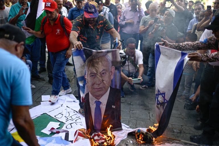 afp_6a646b7c59f8-1784966012 Protesters burn a photograph of Israeli Prime Minister Benjamin Netanyahu alongside an Israeli flag during a rally in Caracas on July 24, 2026, protesting the presence and influence of the United States and Israel in the country, one month after the June 24 earthquakes.