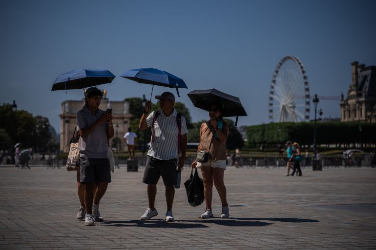 ap_6a3ff8d55a0f4-1782577365 Tourists with umbrellas walk in Paris during a heat wave, Saturday, June 27, 2026. (AP Photo/Aurelien Morissard)