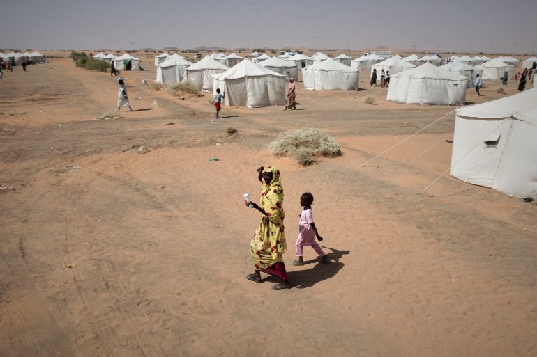 ap_6a4be19f81268-1783357855 FILE - A woman and a child, displaced from North Darfur's capital, el-Fasher or other conflict-affected areas walk in the newly established El-Afadh camp in Al Dabbah, in Sudan's Northern State, Sudan, Thursday, Nov. 13, 2025. (AP Photo/Marwan Ali, File)