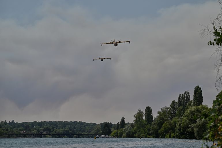 Canadair water bombers fly over the Seine River while fighting wildfires in the Fontainebleau forest region, about 60 kilometers (37 miles) south of Paris, France, Monday, July 13, 2026. (AP Photo/Emma Da Silva)