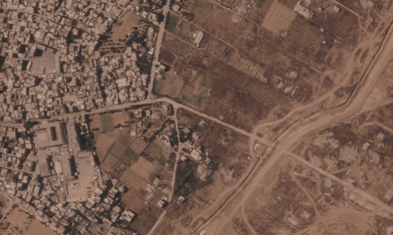 This satellite image from Planet Labs PBC shows a section of an earthen barrier being built by the Israeli military, right side of image moving top to bottom, in the central Gaza Strip, July 1, 2026. At left is the Maghazi refugee camp, and on the other side are homes demolished by the military. (Planet Labs PBC via AP)