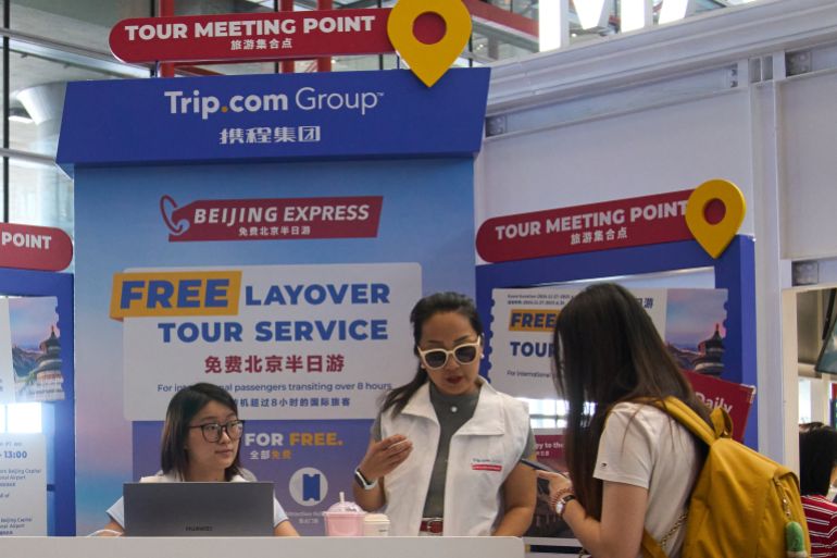 Workers attend to a traveller at a travel agency Trip.com Group's promotion booth in Beijing on June 15, 2025. (AP Photo/Andy Wong)