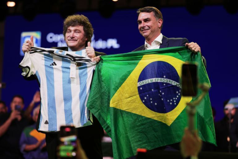 ap_6a655e38e2a52-1785028152 Brazilian Sen. Flavio Bolsonaro holds a Brazil national flag as Argentina's President Javier Milei holds an Argentina local selection jersey, during the Liberal Party convention where Bolsonaro was confirmed as the party's presidential candidate, in Sao Paulo, Saturday, July 25, 2026. (AP Photo/Ettore Chiereguini)