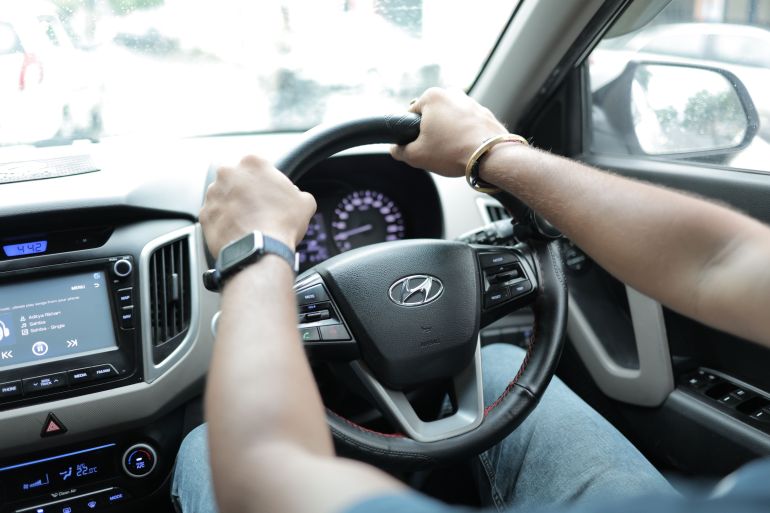 byyk-1785064794 Close-up of a person driving a Hyundai car, showcasing hands on the steering wheel and dashboard detail.