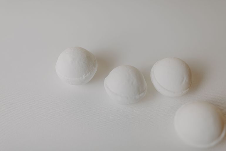 d-6682971-1784379112 Minimalist close-up of several white bath bombs on a clean, light background.