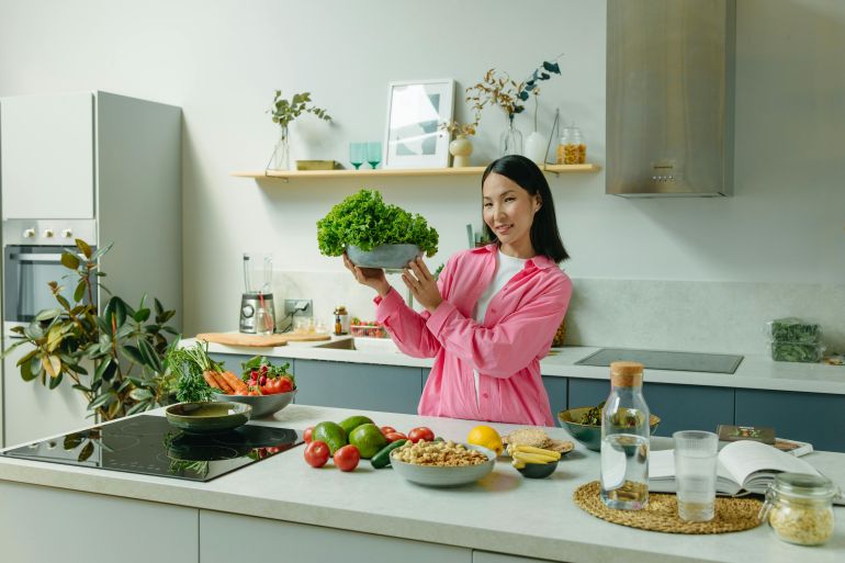 d8b4d8b3d98ad8b4d98a5-1753377547 A Woman in Pink Long Sleeves Standing in the Kitchen while Holding a Bowl of Lettuce