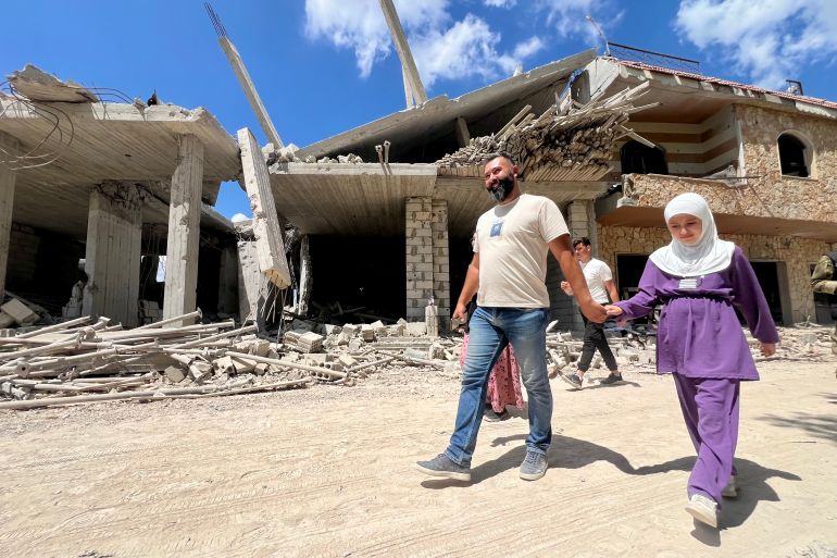 epa_6a660cf4aa90-1785072884 epa13133952 People walk next to destroyed buildings in the village of Zawtar al-Gharbiyeh in southern Lebanon, 26 July 2026. Zawtar al-Gharbiya is among the designated pilot zones under the ceasefire agreement between Lebanon and Israel, from which Israeli forces are scheduled to withdraw. EPA/STRINGER