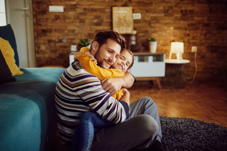feq-1784633340 Affectionate little girl and her father embracing while relaxing in the living room. المصدر فري بيك