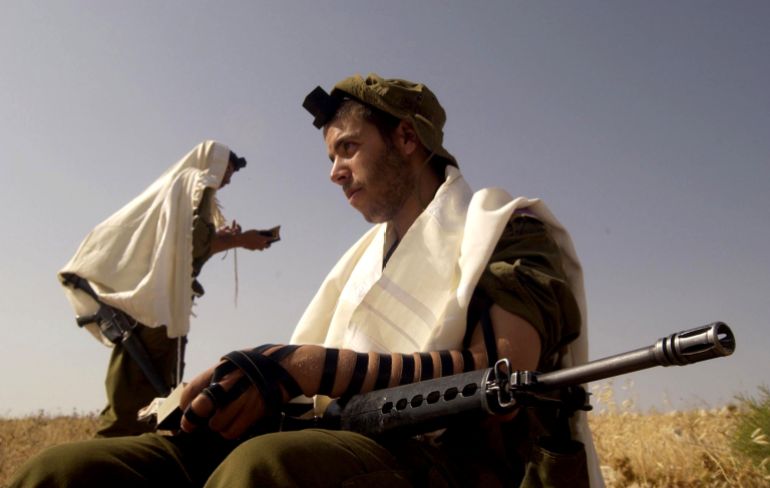 ISRAEL - JUNE 23: In this handout photo from the Israeli Defense Forces (IDF), ultra-Orthodox Jewish volunteers to the IDF's Nahal Haredi brigade wear prayer shawls as they recite their morning prayers during survival training at an unidentified base June 23, 2005 somewhere in Israel. The unit is made up of the religious Jewish soldiers who are not required to serve in the Israeli army. (Photo by Abir Sultan/IDF via Getty Images)