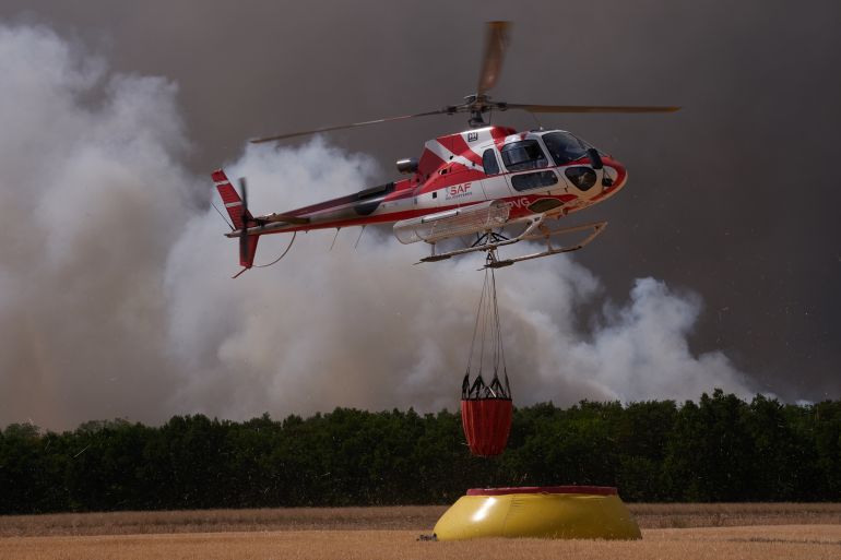 FONTAINEBLEAU, FRANCE - JULY 13: Firefighting helicopters with a suspended water bucket collect water from a temporary reservoir established by firefighters and local farmers to combat the wildfire, after a wildfire broke out in the Fontainebleau Forest on July 13, 2026 in Fontainebleau, France. The fire began yesterday in the former royal hunting preserve, which is about 40 miles outside Paris. (Photo by Pierre Crom/Getty Images)