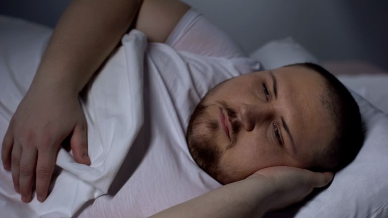 gettyimages-1088258086-1783884714 Overweight man in bed trying to fall asleep, health disorder, insomnia, anxiety