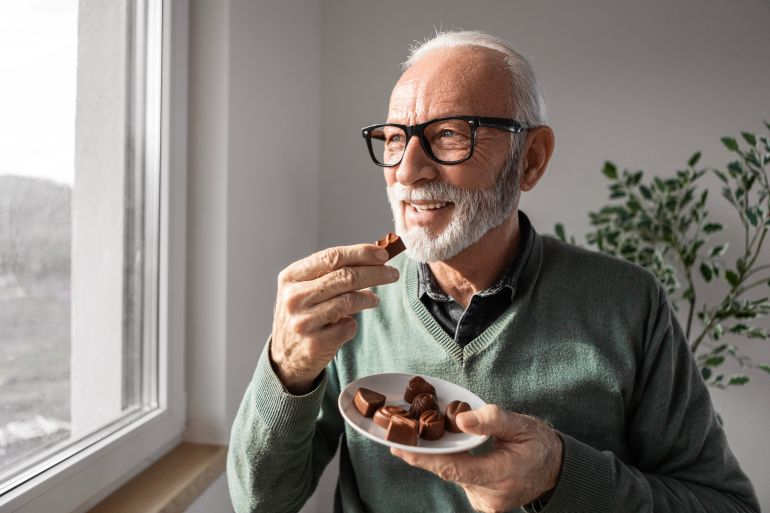 gettyimages-2197445179-1783351300 Senior man eating chocolate at home