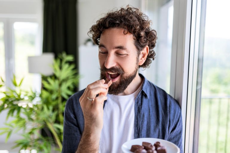 gettyimages-2217282383-1783351314 Young handsome man eating chocolate