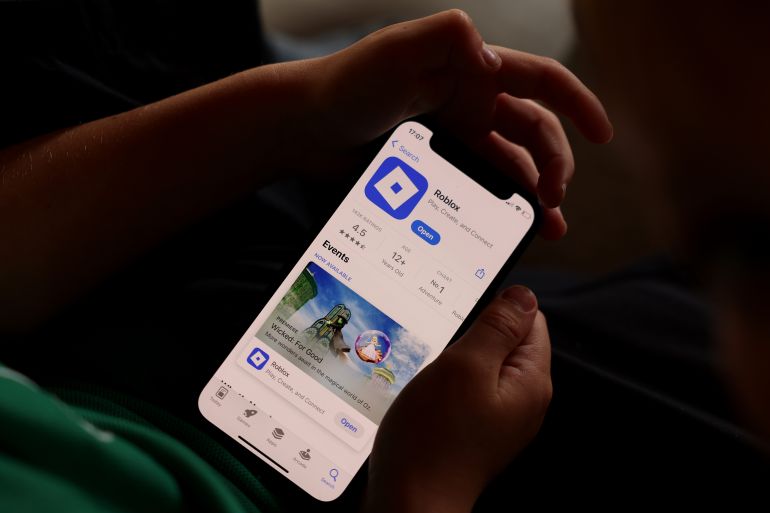 gettyimages-2247401744-1763557455 AUCKLAND, NEW ZEALAND - NOVEMBER 19: In this photo illustration, young children hold an iPhone while using the online game platform Roblox on November 19, 2025 in Auckland, New Zealand. Roblox will block in-game chat for users under 13 unless they complete mandatory age verification, tightening safety controls across the platform. The changes will take effect in Australia, New Zealand and the Netherlands in December, and the rest of the world in January, 2026. (Photo illustration by Getty Images)