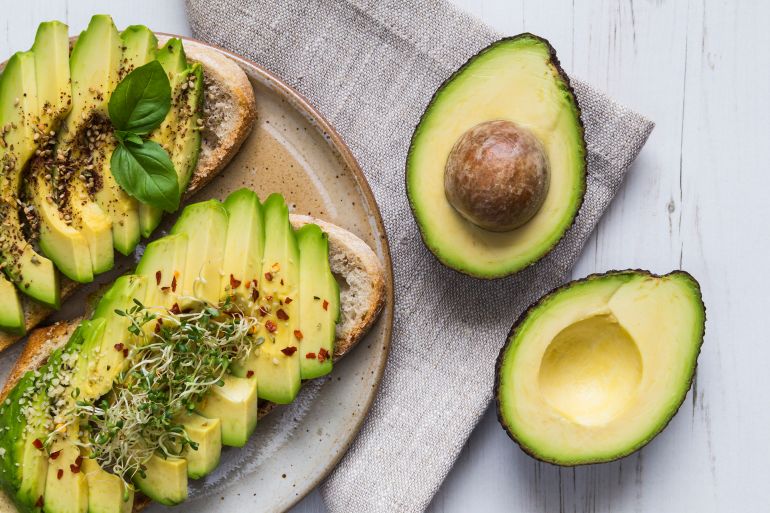 gettyimages-544809990-1735831783 Toast with sliced avocado topping, basil leaf and seasoning.