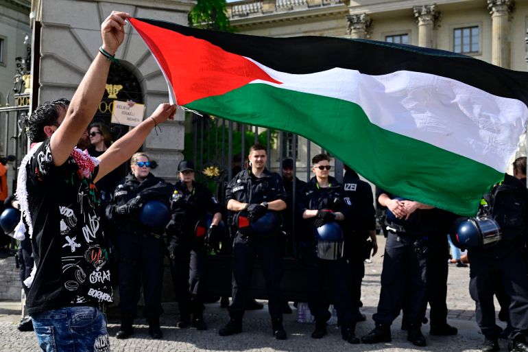 pic-855443-1783198450 A demonstrator displays the Palestinian flag as police block the university entrance after people staged a pro-Gaza sit-in in solidarity with the Palestinian people in front of Berlin's Humboldt University, on May 3, 2024. (Photo by JOHN MACDOUGALL / AFP)