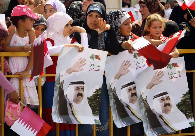 سكان من جنوب لبنان يحملون صورًا لأمير قطر آنذاك الشيخ حمد بن خليفة آل ثاني أثناء زيارته بلدة بنت جبيل في 31 يوليو/تموز 2010 (رويترز)