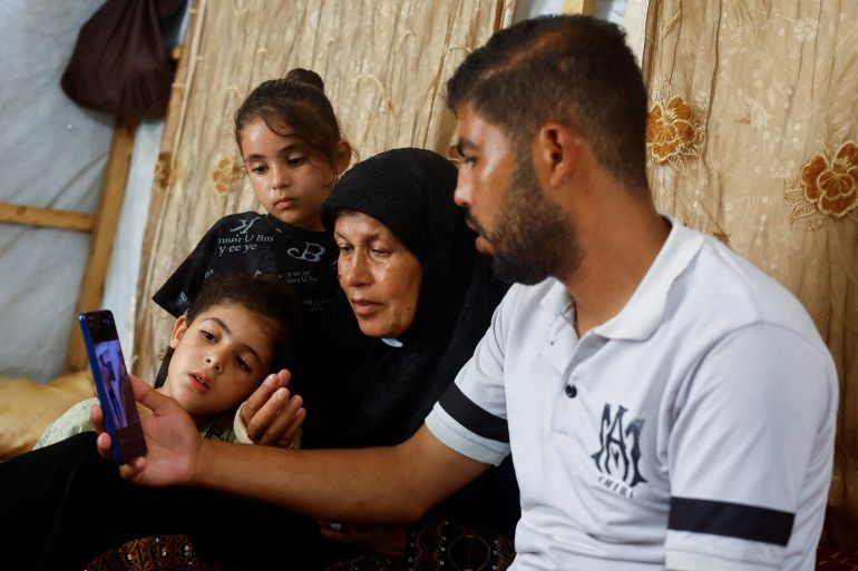 reuters_6a4964c8-1783194824 Joudeh Al-Ghoul, mother of Palestinian prisoner Amin Al-Ghoul who is held by Israel, and family members look at a mobile phone displaying a widely circulated image they believe show him in Israeli custody, in Gaza City, July 4, 2026. REUTERS/Mahmoud Issa