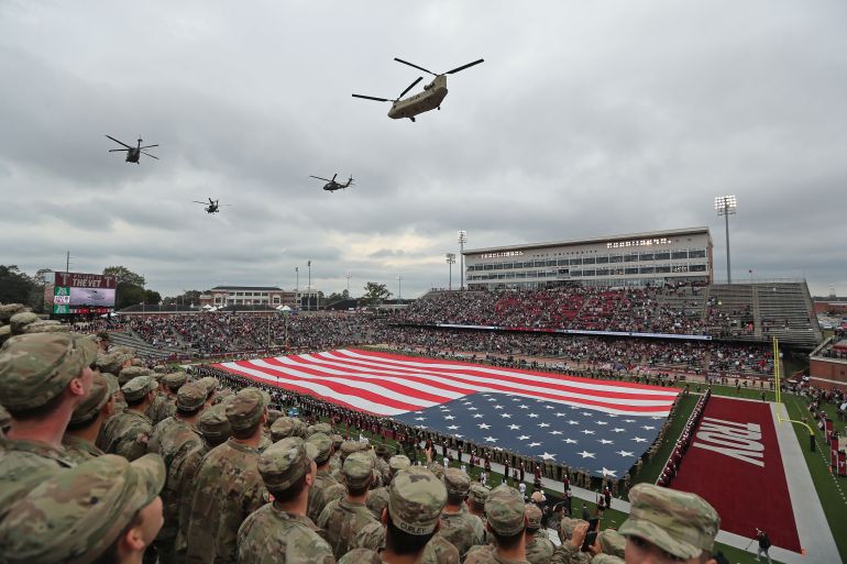 reuters_6a5b8c9e-1784384670 Nov 12, 2022; Troy, Alabama, USA; U.S. Army soldiers from Fort Benning, Georgia watch a military helicopter flyover during the national anthem over an American flag before a game between the Army Black Knights and the Troy Trojans during the first half at Veterans Memorial Stadium. Mandatory Credit: Danny Wild-USA TODAY Sports