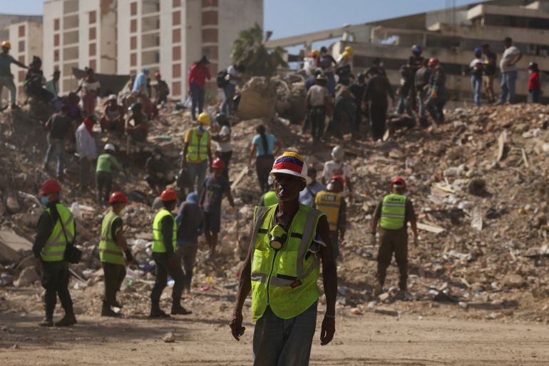 reuters_6a5ba89d-1784391837 A search and rescue volunteer wearing a Venezuelan flag attached to his helmet searches debris alongside other people, in the aftermath of the June 24 earthquakes, in La Guaira, Venezuela, July 16, 2026. REUTERS/Leonardo Fernandez Viloria