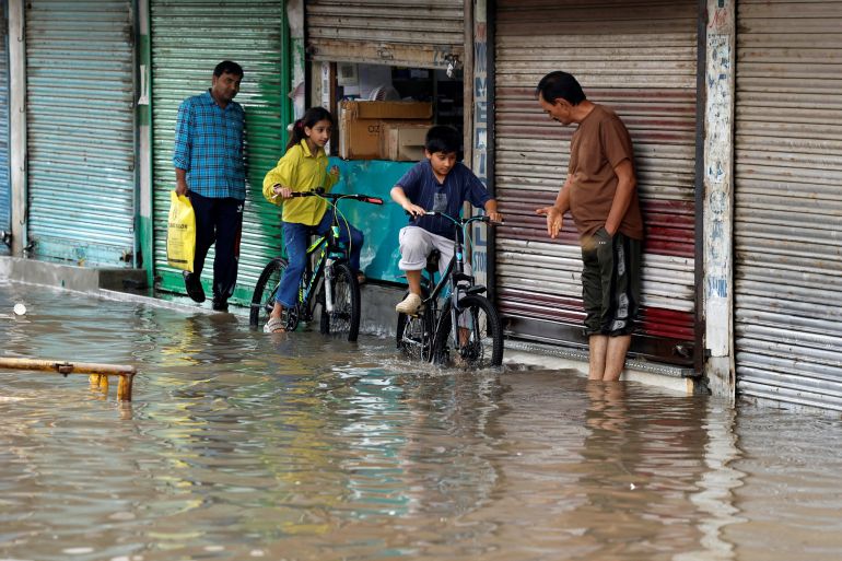 Children ride their bicycles on the side of a water-logged street after heavy rainfall in Srinagar, Indian Kashmir, July 20, 2026. REUTERS/Sharafat Ali