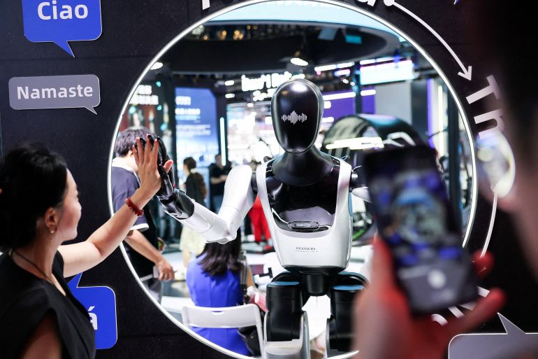 reuters_6a5e1df3-1784552947 A visitor high-fives a humanoid robot at the Keenon Robotics booth during the World Artificial Intelligence Conference (WAIC) in Shanghai, China, July 18, 2026. REUTERS/Go Nakamura TPX IMAGES OF THE DAY