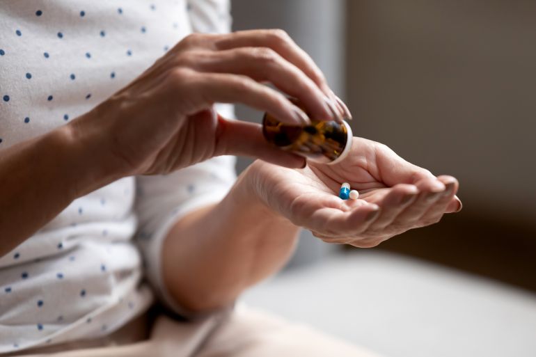 Close up 60s old woman pours out from bottle pills time to take medicaments, cure for memory loss, high blood pressure or cholesterol level remedy pain killer drugs, senile diseases treatments concept