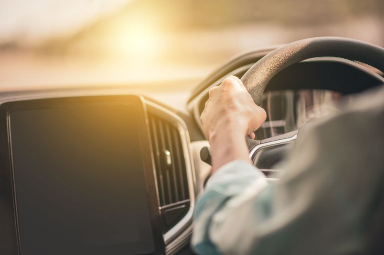 2570131-4160236-1-1786032895 A person steering a car with sunlight streaming through the window, creating a warm ambiance.