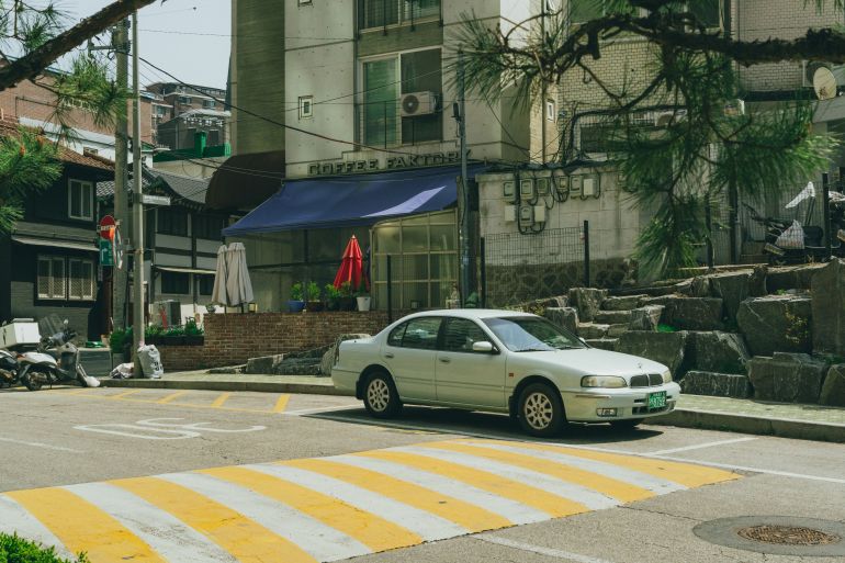 Charming street view in Seoul featuring a vintage car parked near a local coffee shop surrounded by urban architecture.