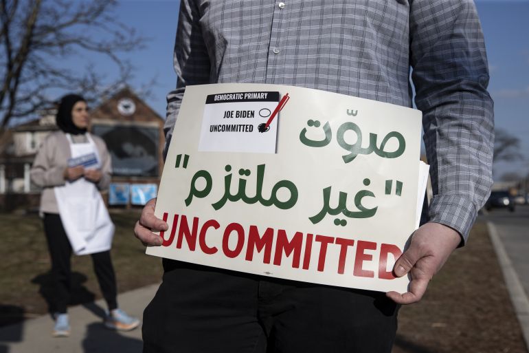 33837487-1712310461 أمريكي يحمل لافتة تدعو للتصويت بـ"غير ملتزم" خلال الانتخابات التمهيدية في ديربورن احتجاجا على سياسة بايدن تجاه غزة