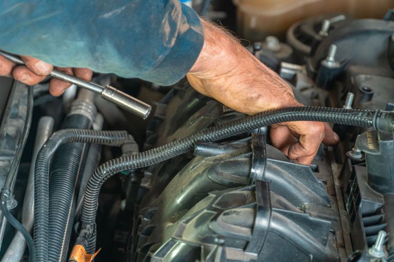 4116221-1786036468 Detailed image of a mechanic repairing a car engine, showcasing technical expertise.
